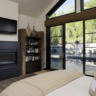 Modelo de dormitorio tipo loft, rural, de tamaño medio, con paredes blancas, suelo de madera clara, chimenea tradicional y marco de chimenea de yeso