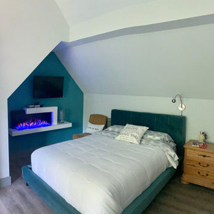 Immagine di una camera da letto bohémian di medie dimensioni con camino sospeso, pavimento grigio e soffitto a volta