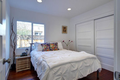 Small trendy master medium tone wood floor bedroom photo in Los Angeles with white walls
