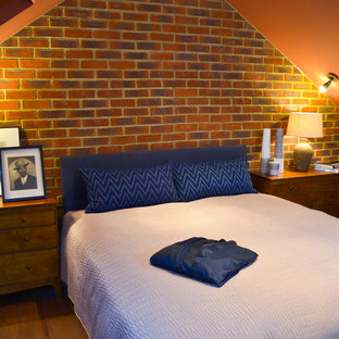 Modelo de dormitorio tipo loft, clásico, de tamaño medio, con parades naranjas y suelo de madera en tonos medios
