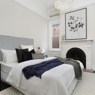 Contemporary bedroom in Sydney with white walls, painted wood floors, a standard fireplace and black floor.