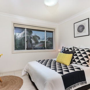 Beach style guest bedroom in Sydney with beige walls and beige floor.