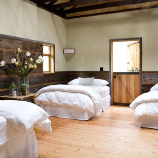 Diseño de habitación de invitados campestre, grande, sin chimenea, con paredes beige, suelo de madera clara y suelo naranja