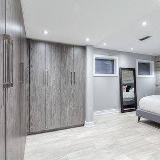 Ejemplo de dormitorio tipo loft, contemporáneo, de tamaño medio, con paredes grises, suelo laminado y suelo marrón