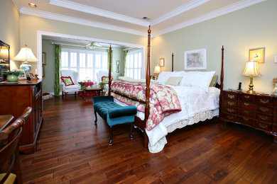 Diseño de dormitorio principal clásico grande sin chimenea con paredes verdes, suelo de madera en tonos medios y suelo marrón