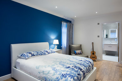 Ispirazione per una camera da letto contemporanea di medie dimensioni con pavimento in laminato, pavimento beige, pareti blu e nessun camino