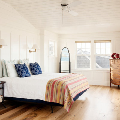 Example of a beach style medium tone wood floor bedroom design in Boston with white walls and no fireplace