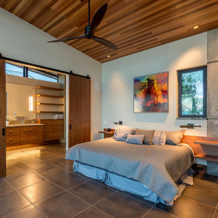 Diseño de dormitorio tipo loft, moderno, pequeño, con paredes amarillas, suelo de baldosas de porcelana, chimenea de doble cara, marco de chimenea de piedra y suelo beige