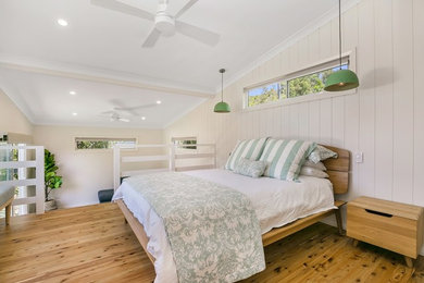 セントラルコーストにあるビーチスタイルのおしゃれな寝室 (白い壁、無垢フローリング、茶色い床) のレイアウト