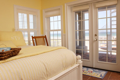 Mid-sized beach style guest ceramic tile and orange floor bedroom photo in Other with yellow walls
