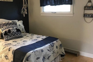 ポートランド(メイン)にある中くらいなビーチスタイルのおしゃれな客用寝室 (青い壁、淡色無垢フローリング)
