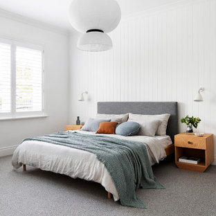 Mid-sized beach style master bedroom in Melbourne with white walls, carpet, a corner fireplace and grey floor.