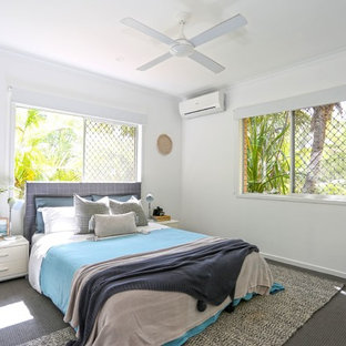 This is an example of a beach style guest bedroom in Other with white walls, carpet and grey floor.