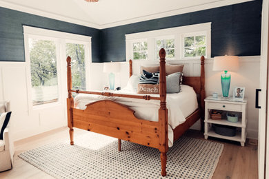 Diseño de dormitorio principal marinero con suelo de madera clara y papel pintado