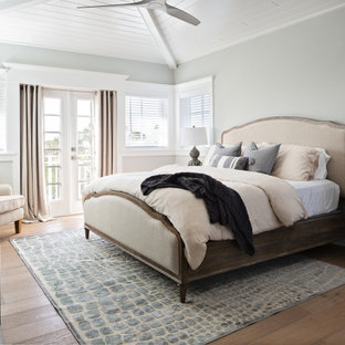 Großes Maritimes Hauptschlafzimmer mit grauer Wandfarbe, braunem Holzboden, beigem Boden und Holzwänden in Tampa