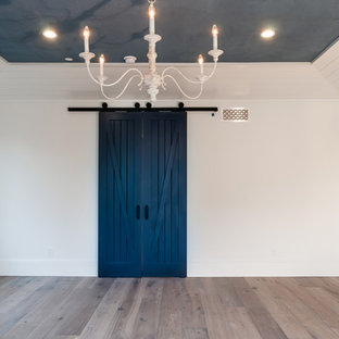 Diseño de dormitorio principal, marinero, grande, con paredes blancas, suelo de madera clara, chimenea tradicional y marco de chimenea de ladrillo