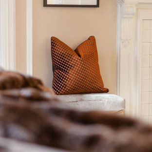 Imagen de dormitorio principal, minimalista, grande, con paredes beige, suelo de madera en tonos medios, chimenea tradicional, marco de chimenea de hormigón y suelo marrón