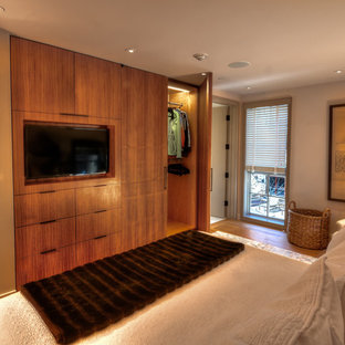 Modelo de dormitorio principal, contemporáneo, de tamaño medio, sin chimenea, con paredes beige, suelo de madera en tonos medios y suelo marrón