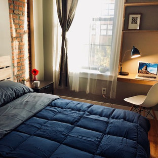 Diseño de dormitorio tipo loft, contemporáneo, de tamaño medio, sin chimenea, con paredes beige, suelo de madera clara, marco de chimenea de ladrillo y suelo beige