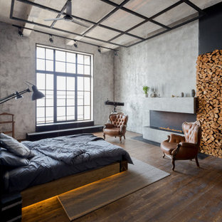 Imagen de dormitorio urbano con paredes grises, suelo de madera oscura, chimenea lineal y suelo marrón