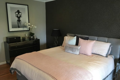Imagen de dormitorio principal moderno con paredes grises y suelo de madera en tonos medios