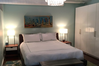 Small trendy master medium tone wood floor bedroom photo in Los Angeles with blue walls