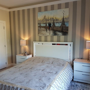 Modelo de dormitorio actual con paredes beige, suelo laminado, chimeneas suspendidas, marco de chimenea de baldosas y/o azulejos y suelo beige