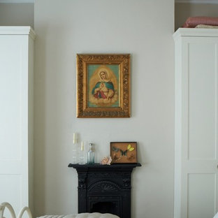 Imagen de dormitorio principal, ecléctico, de tamaño medio, con paredes beige, chimenea tradicional y marco de chimenea de metal