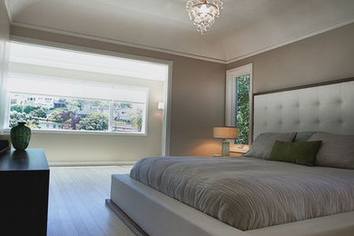 Modelo de dormitorio principal clásico renovado de tamaño medio sin chimenea con paredes beige y suelo de bambú