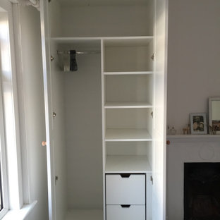 Esempio di una grande camera matrimoniale design con pareti bianche, pavimento in legno verniciato, camino classico, cornice del camino in intonaco e pavimento bianco