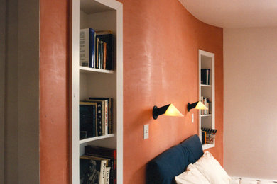 Cette image montre une chambre parentale minimaliste avec un mur rouge.