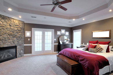 Transitional master carpeted bedroom photo in Charlotte with gray walls, a standard fireplace and a stone fireplace