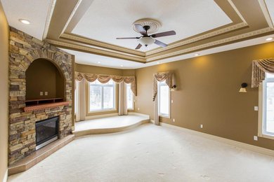 Bedroom - large master carpeted bedroom idea in Edmonton with brown walls and a stone fireplace