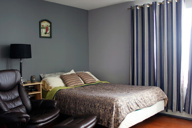 Ejemplo de dormitorio sin chimenea con paredes grises y suelo de madera en tonos medios