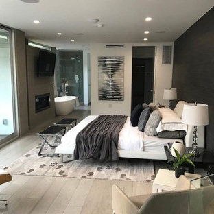 Diseño de dormitorio principal, moderno, de tamaño medio, con paredes blancas, suelo de madera clara, marco de chimenea de hormigón y suelo beige