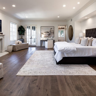Modelo de dormitorio principal, mediterráneo, con suelo de madera oscura, marco de chimenea de hormigón y suelo marrón