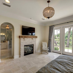 Imagen de dormitorio principal, clásico renovado, grande, con paredes beige, suelo de travertino, chimenea de doble cara y marco de chimenea de ladrillo