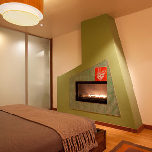 Ejemplo de dormitorio principal, minimalista, grande, con paredes blancas, suelo de bambú, chimenea tradicional y marco de chimenea de baldosas y/o azulejos