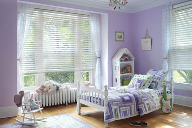 Imagen de dormitorio tradicional de tamaño medio sin chimenea con paredes púrpuras, suelo de madera clara y suelo beige