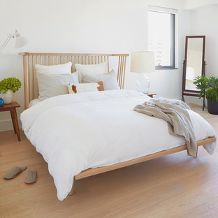 Imagen de dormitorio principal, escandinavo, pequeño, con paredes blancas, suelo de madera clara, chimenea de doble cara, marco de chimenea de piedra y suelo beige