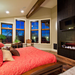 Foto di una camera da letto american style con pareti beige, pavimento in legno massello medio, camino lineare Ribbon e cornice del camino piastrellata