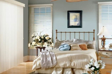 Imagen de dormitorio principal marinero de tamaño medio sin chimenea con paredes azules, suelo de madera clara y suelo marrón