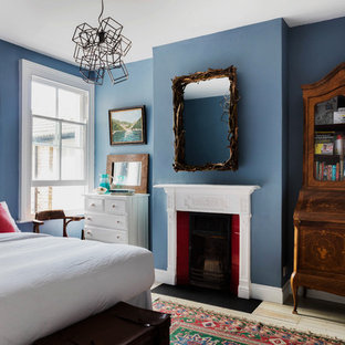 Diseño de habitación de invitados tradicional, de tamaño medio, con paredes azules, suelo de madera clara, chimenea tradicional y marco de chimenea de madera