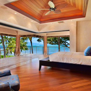 Diseño de dormitorio principal, tropical, grande, sin chimenea, con paredes beige, suelo de madera en tonos medios y suelo marrón