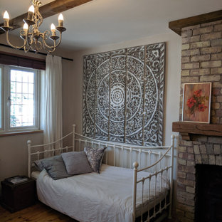 Foto de habitación de invitados ecléctica con paredes grises, suelo de madera clara, estufa de leña, marco de chimenea de ladrillo y suelo beige