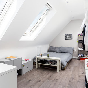 Diseño de dormitorio tipo loft, minimalista, de tamaño medio, sin chimenea, con paredes beige, suelo laminado y suelo marrón