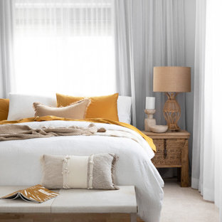 Photo of a large beach style master bedroom in Brisbane with carpet, beige floor and beige walls.