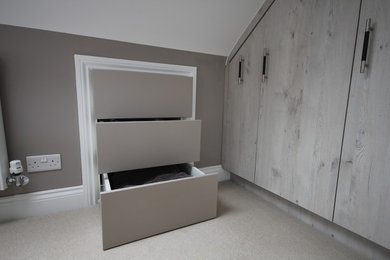 This is an example of a medium sized contemporary master bedroom in London with grey walls, carpet and no fireplace.