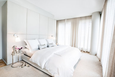 Diseño de dormitorio principal contemporáneo con paredes blancas, suelo de madera clara y suelo beige