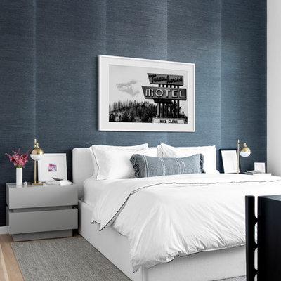 Example of a trendy light wood floor and beige floor bedroom design in New York with blue walls